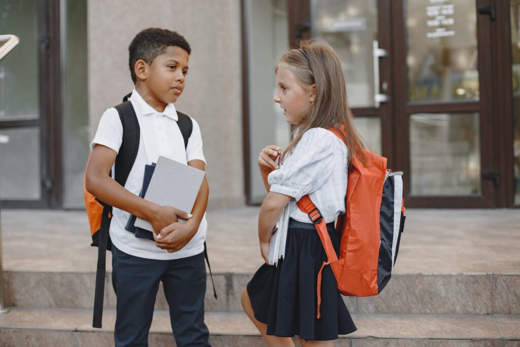 A Girl and Boy Wearing Their School Uniforms Standing on Concrete Stairs